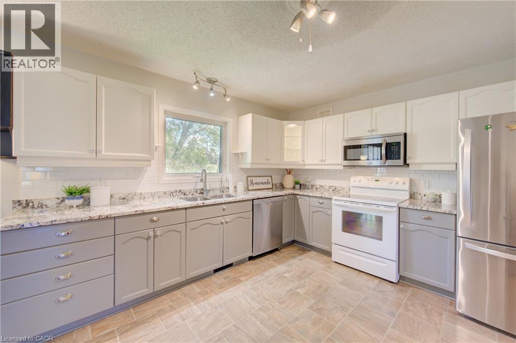 Kitchen with two-tone cabinetry, stainless steel appliances, granite-style countertops, and a subway tile backsplash - 137 Wesley Crescent, Waterloo, ON