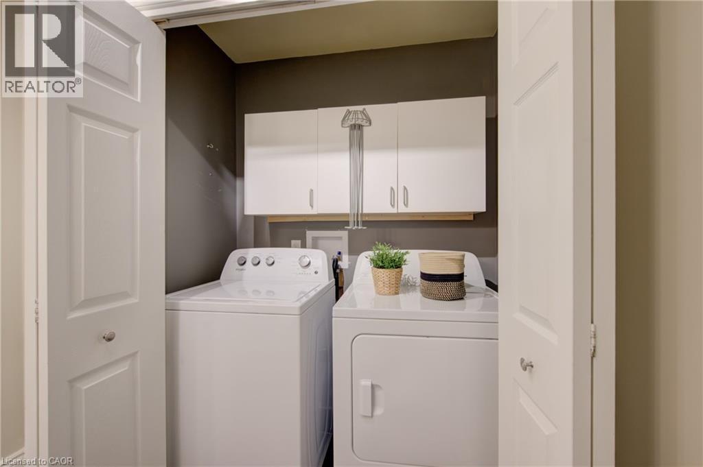 Dedicated laundry area featuring a washer and dryer, white panel bi-fold doors, white upper cabinetry, and a wood-finish shelf - 137 Wesley Crescent, Waterloo, ON