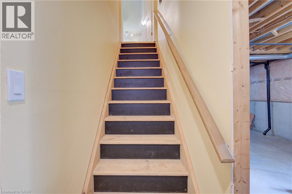 Staircase with light wood stringers, black risers, and a natural wood handrail - 137 Wesley Crescent, Waterloo, ON