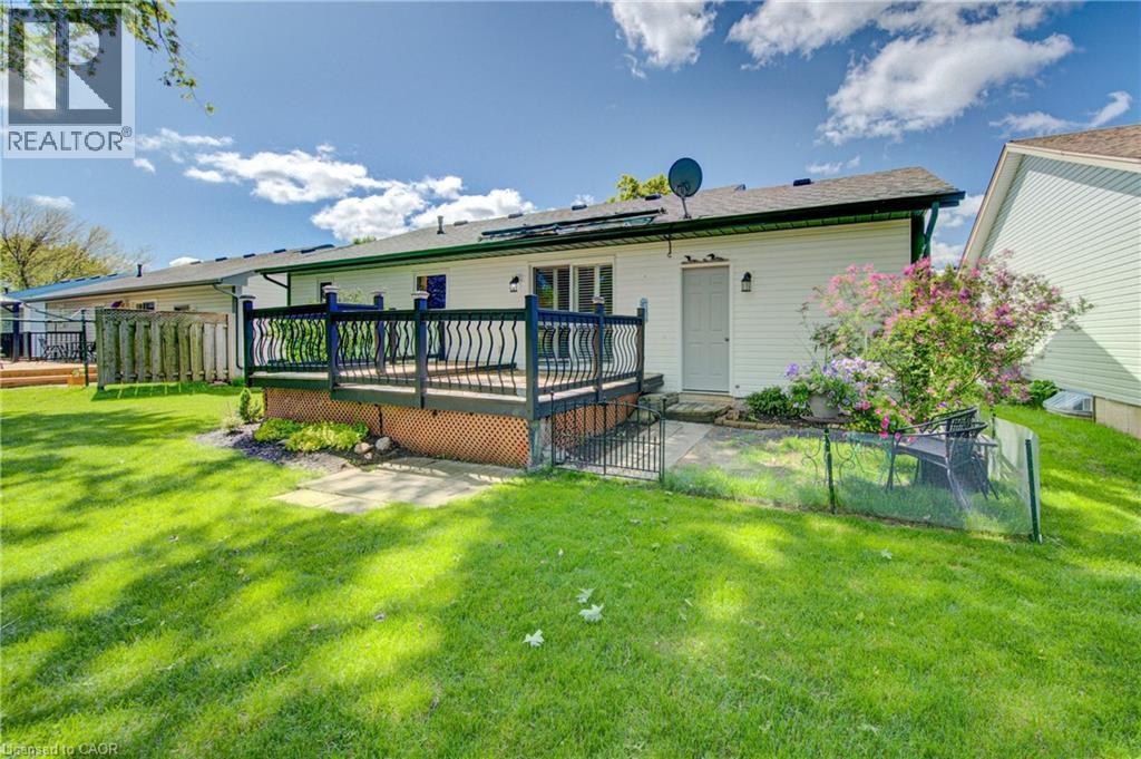 Expansive backyard featuring a multi-level deck with black railings, a patio area with stone pavers, and mature landscaping with flowering shrubs - 137 Wesley Crescent, Waterloo, ON