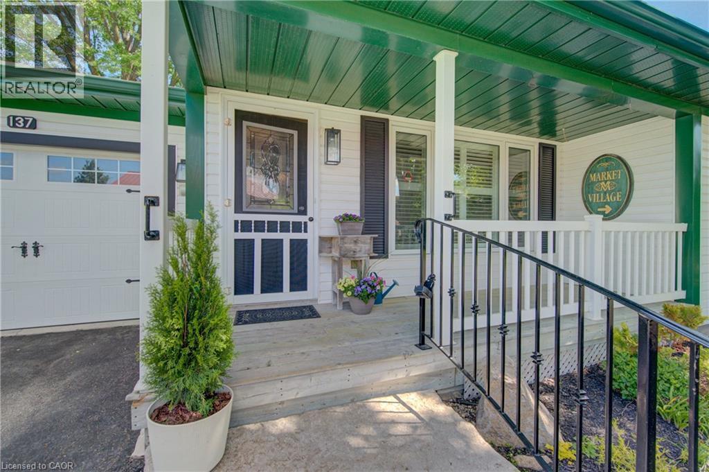 Covered porch entry featuring a decorative storm door, white siding, and a contrasting green ceiling detail - 137 Wesley Crescent, Waterloo, ON