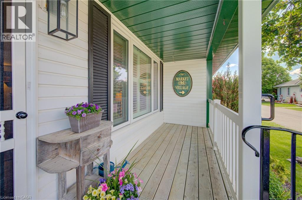 Covered front porch featuring wood-finish flooring, white siding, and a green soffit - 137 Wesley Crescent, Waterloo, ON