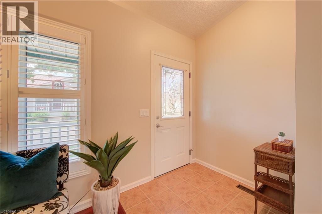 Entryway featuring terracotta-style floor tiling, a white door with decorative glass inserts, and a window with white plantation shutters - 137 Wesley Crescent, Waterloo, ON