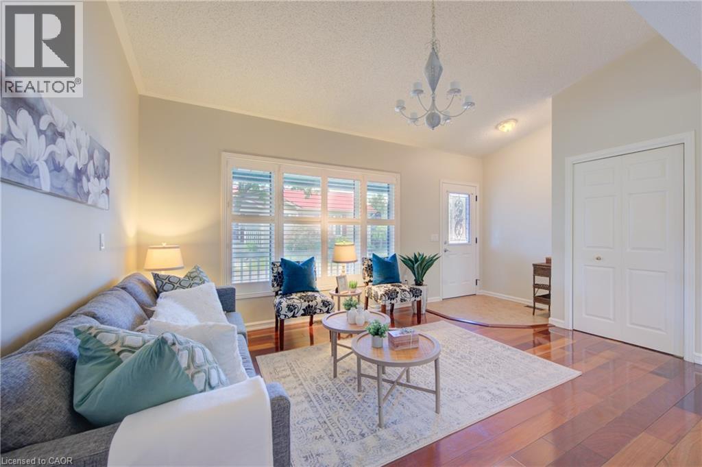 Bright living area featuring wood-finish flooring, vaulted ceilings, and large windows with horizontal blinds - 137 Wesley Crescent, Waterloo, ON