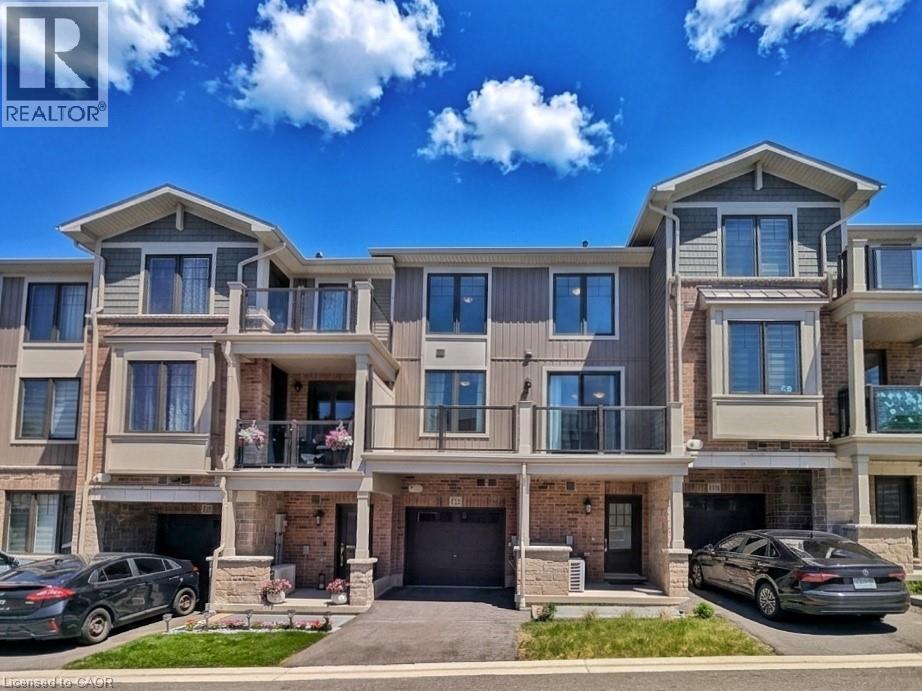 Modern townhome exterior featuring multi-level balconies with glass railings, an attached garage, brick and siding facade, and a covered entry - 10 Birmingham Drive Unit# 129, Cambridge, ON - Outdoor With Balcony With Facade