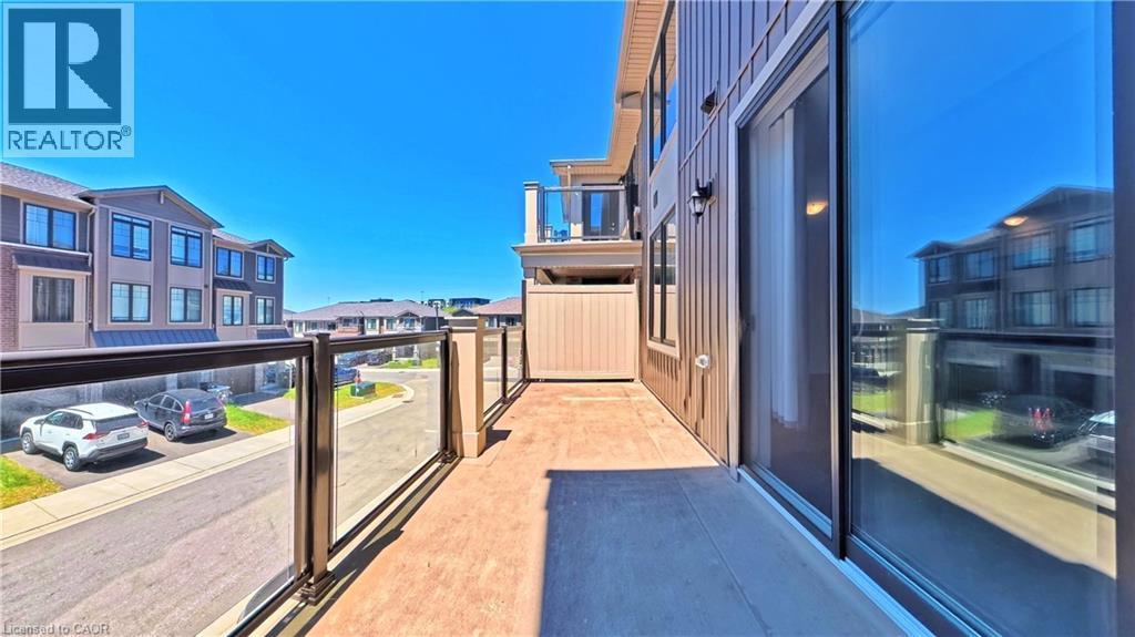 Outdoor balcony featuring glass panel railings with dark frames, a sliding glass door, and a textured floor surface - 10 Birmingham Drive Unit# 129, Cambridge, ON - Outdoor With Balcony