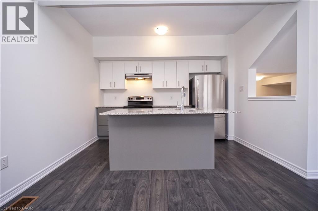 Kitchen featuring a central island with a granite-style countertop, white cabinetry with brushed nickel hardware, and stainless steel appliances - 10 Birmingham Drive Unit# 129, Cambridge, ON - Indoor Photo Showing Kitchen With Stainless Steel Kitchen With Upgraded Kitchen