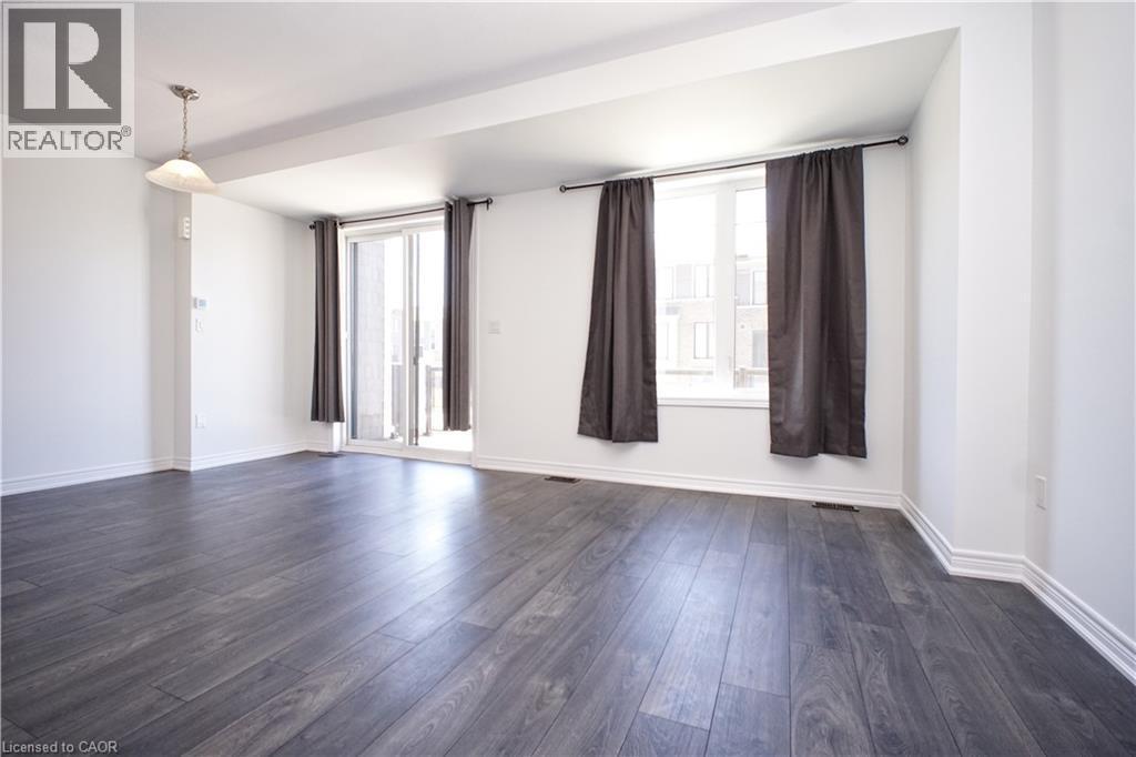 Spacious interior featuring dark wood-finish flooring, white baseboards, and a neutral wall palette - 10 Birmingham Drive Unit# 129, Cambridge, ON - Indoor Photo Showing Other Room
