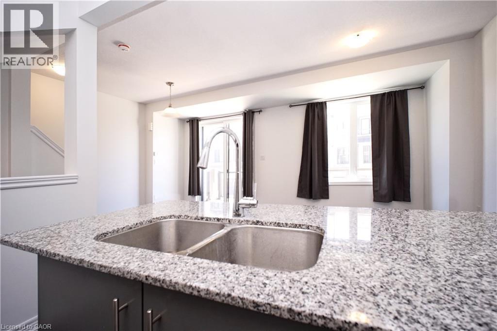 Kitchen island with a double basin stainless steel sink, a chrome gooseneck faucet, and a light-toned granite countertop - 10 Birmingham Drive Unit# 129, Cambridge, ON - Indoor Photo Showing Kitchen With Double Sink