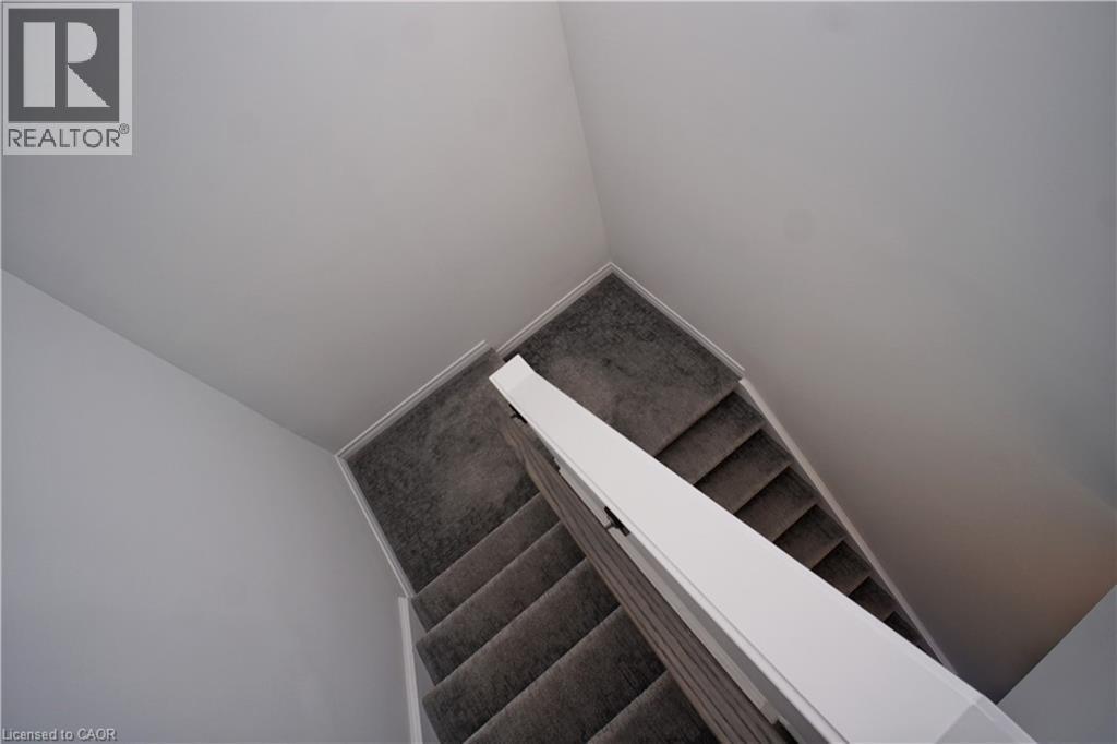 Staircase with gray carpeted treads and risers, framed by white walls and a white handrail - 10 Birmingham Drive Unit# 129, Cambridge, ON - Indoor Photo Showing Other Room