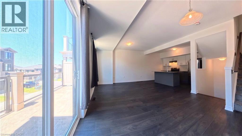 Open concept living space featuring dark wood-finish flooring, a modern pendant light fixture, and recessed lighting - 10 Birmingham Drive Unit# 129, Cambridge, ON - Indoor Photo Showing Other Room