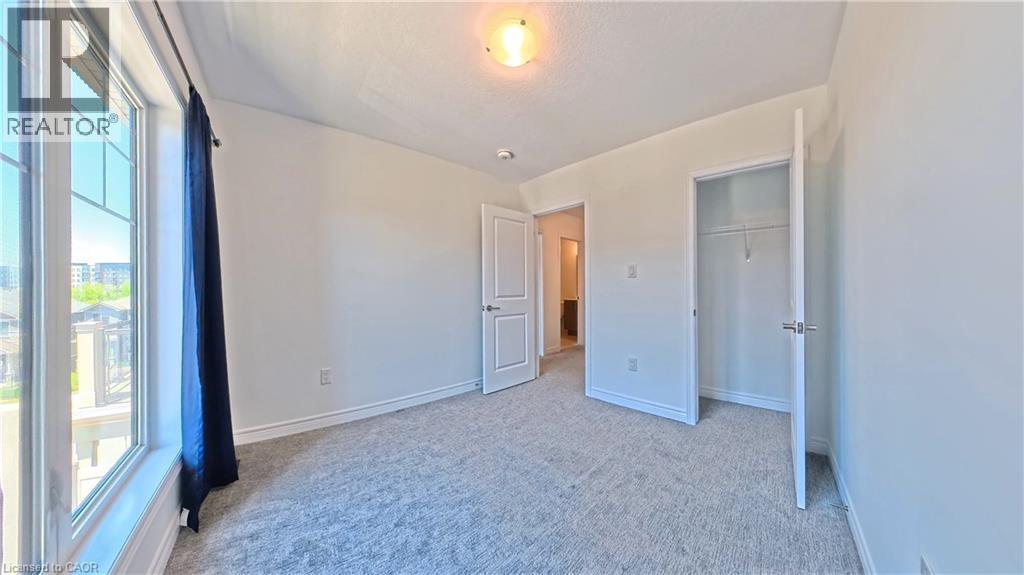 Bright room featuring a large window with multiple panes, neutral carpeting, white trim, and a white interior door - 10 Birmingham Drive Unit# 129, Cambridge, ON - Indoor Photo Showing Other Room