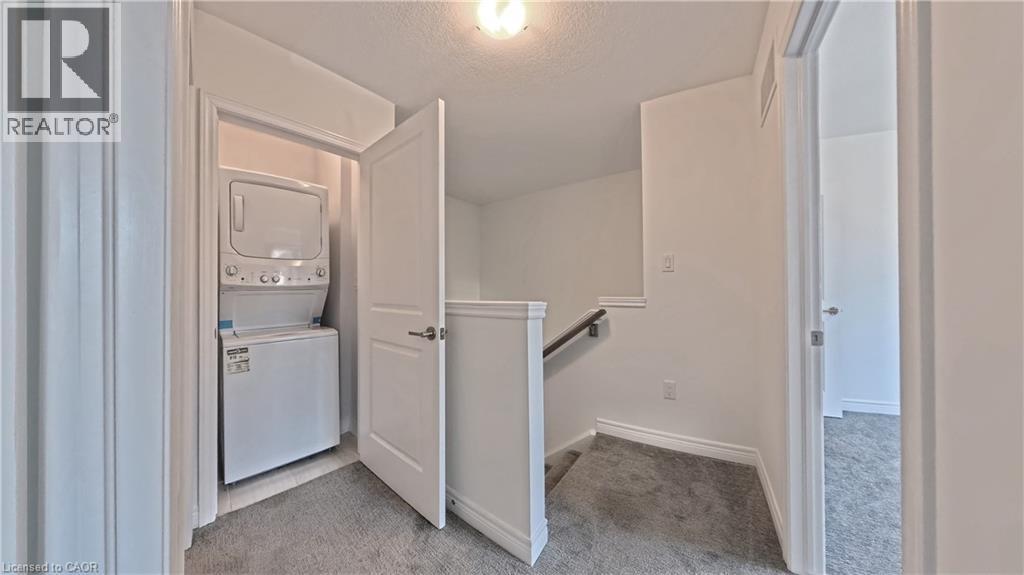 Integrated laundry closet with stacked appliances - 10 Birmingham Drive Unit# 129, Cambridge, ON - Indoor Photo Showing Laundry Room