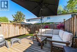 Private backyard patio featuring wood decking, a wooden privacy fence, and green space -