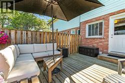 Private wood deck featuring a wooden privacy fence, brick exterior with white siding, and a white exterior door -