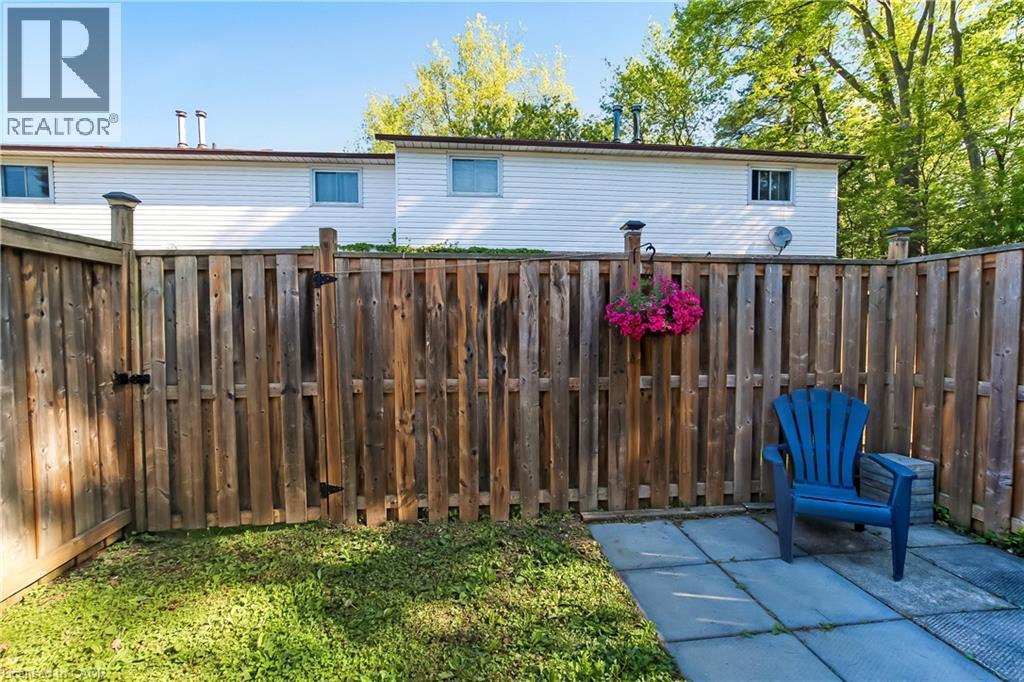Private backyard featuring a wooden privacy fence, a paved patio area, and a grassy section - 218 Richardson Drive Unit# 26, Port Dover, ON