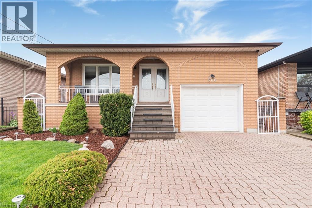 Brick facade residence featuring a covered front porch, integrated single-car garage, terraced front steps, and a paver driveway - 366 Berkindale Drive, Hamilton, ON