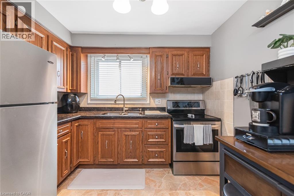 Kitchen featuring wood cabinetry, stainless steel appliances, dark stone countertops, and a tile backsplash - 366 Berkindale Drive, Hamilton, ON