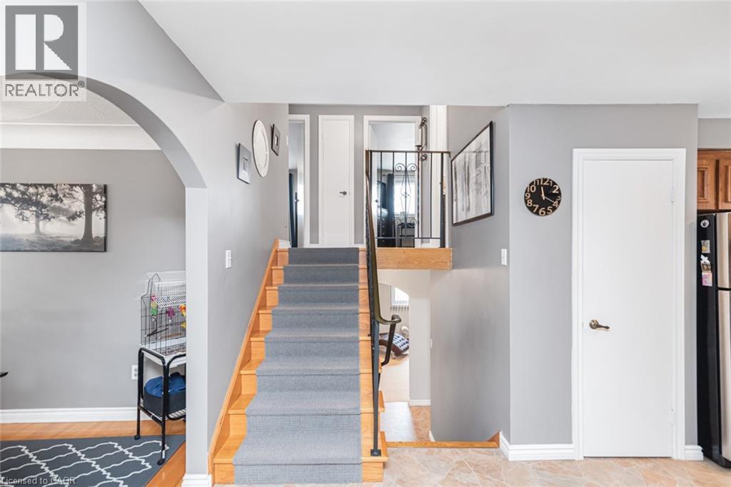 Multi-level interior featuring a carpeted staircase with wood-finish risers, an arched entryway, and neutral wall tones - 366 Berkindale Drive, Hamilton, ON