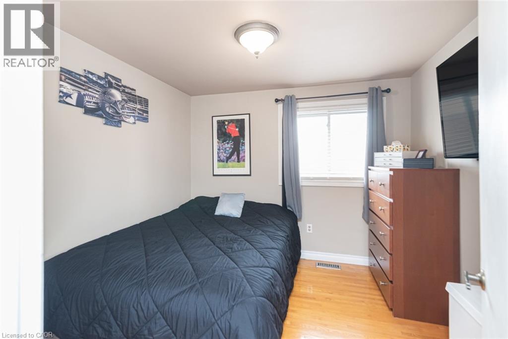 Bedroom featuring wood-finish flooring, a window with blinds, and a flush-mount ceiling light fixture - 366 Berkindale Drive, Hamilton, ON