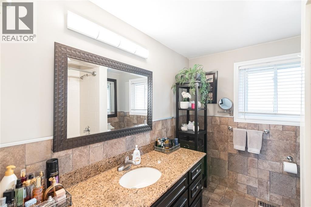 Bathroom vanity featuring a light-toned granite countertop, undermount sink, and dark wood cabinetry - 366 Berkindale Drive, Hamilton, ON