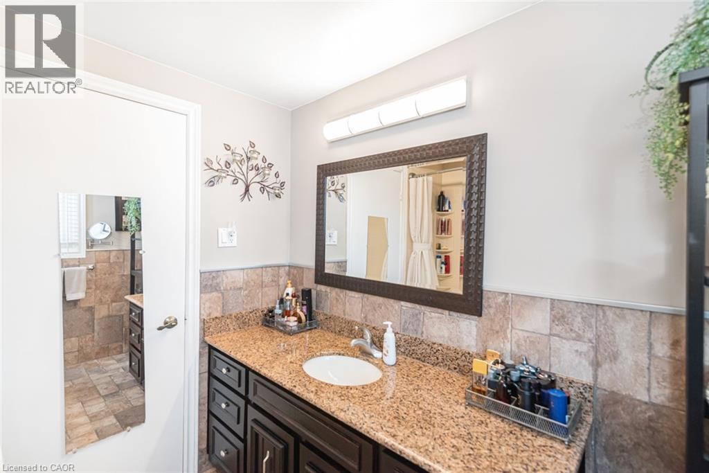 Bathroom vanity featuring a single basin, granite countertop, and dark wood-finish cabinetry with multiple drawers - 366 Berkindale Drive, Hamilton, ON