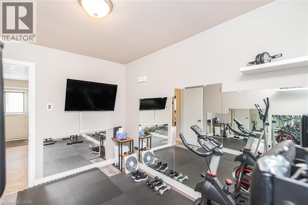 Dedicated fitness space featuring a full-wall mirror, mounted television, and recessed lighting - 366 Berkindale Drive, Hamilton, ON