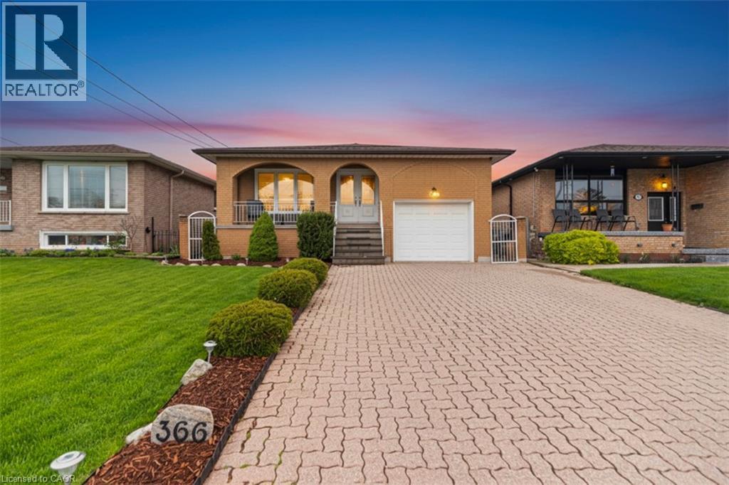 Brick exterior featuring an arched entryway, integrated garage with white door, and a paved driveway - 366 Berkindale Drive, Hamilton, ON