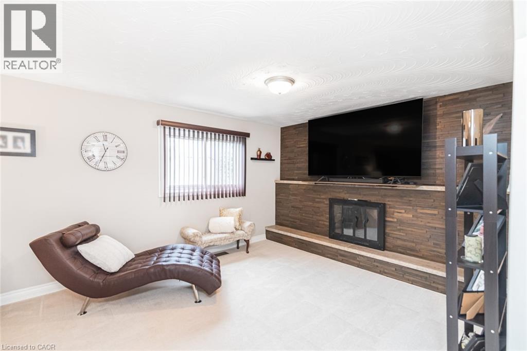 Living area featuring a textured wood-finish fireplace surround, an integrated fireplace unit, and a built-in mantel - 366 Berkindale Drive, Hamilton, ON