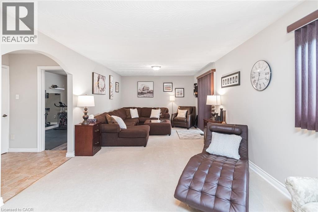 Spacious living area featuring light-toned carpeting, neutral wall finishes, and a textured ceiling - 366 Berkindale Drive, Hamilton, ON