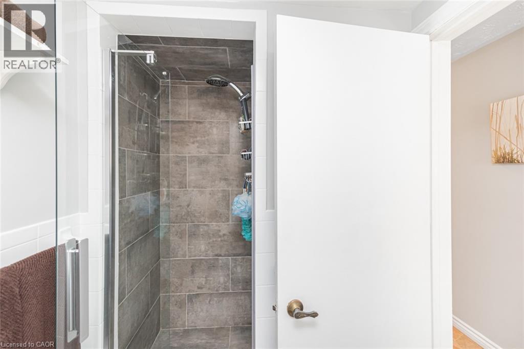 Shower enclosure featuring dark grey rectangular tile, a multi-function showerhead, and a glass panel door with a chrome handle - 366 Berkindale Drive, Hamilton, ON
