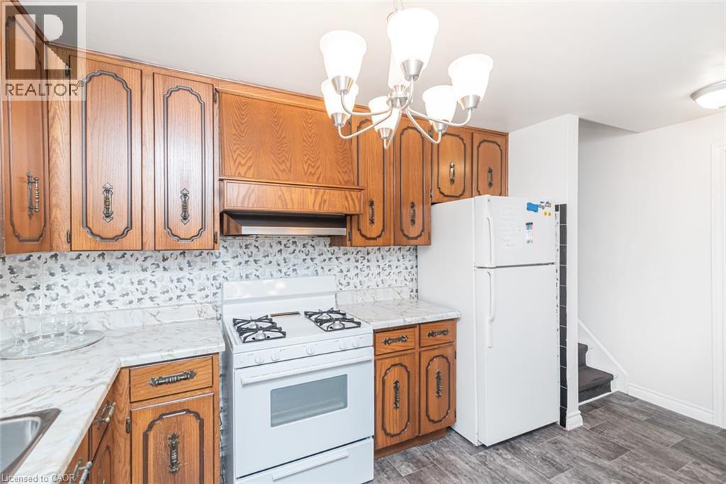 Kitchen featuring wood cabinetry, white appliances, a white gas range, and a patterned tile backsplash - 366 Berkindale Drive, Hamilton, ON