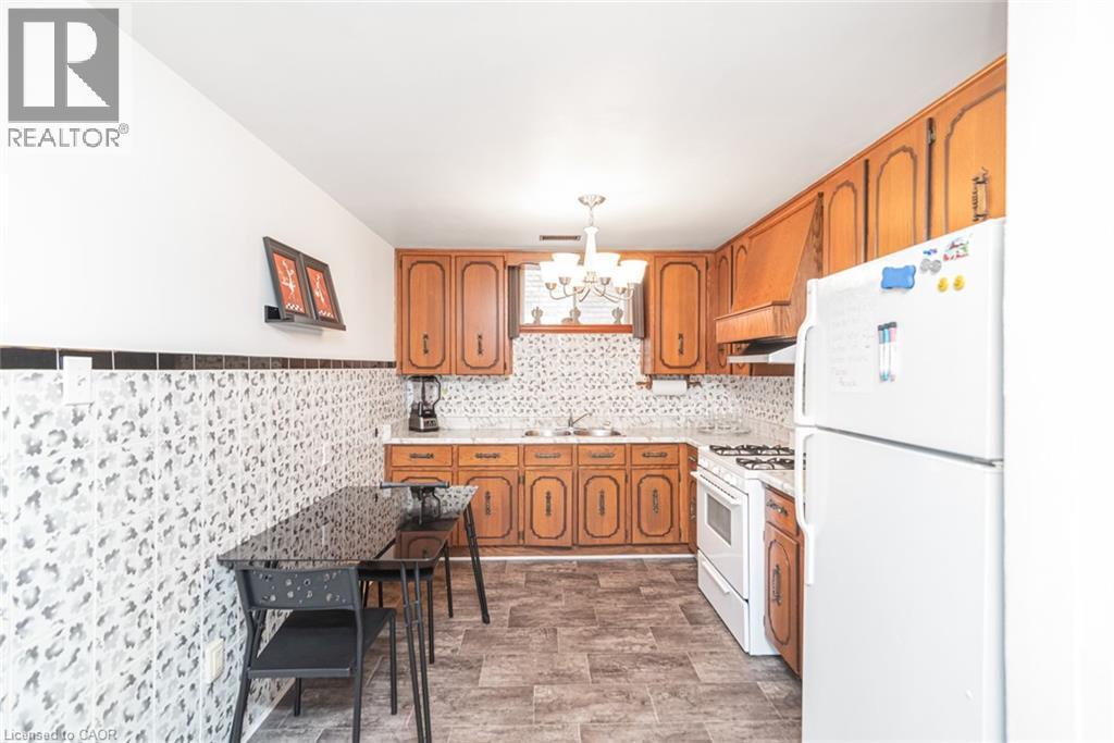 Kitchen featuring wood cabinetry, white appliances, patterned backsplash, and wood-finish flooring - 366 Berkindale Drive, Hamilton, ON