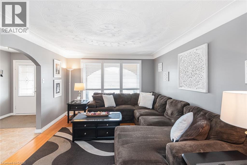 Spacious living area featuring wood-finish flooring, a decorative ceiling, and an arched entryway - 366 Berkindale Drive, Hamilton, ON