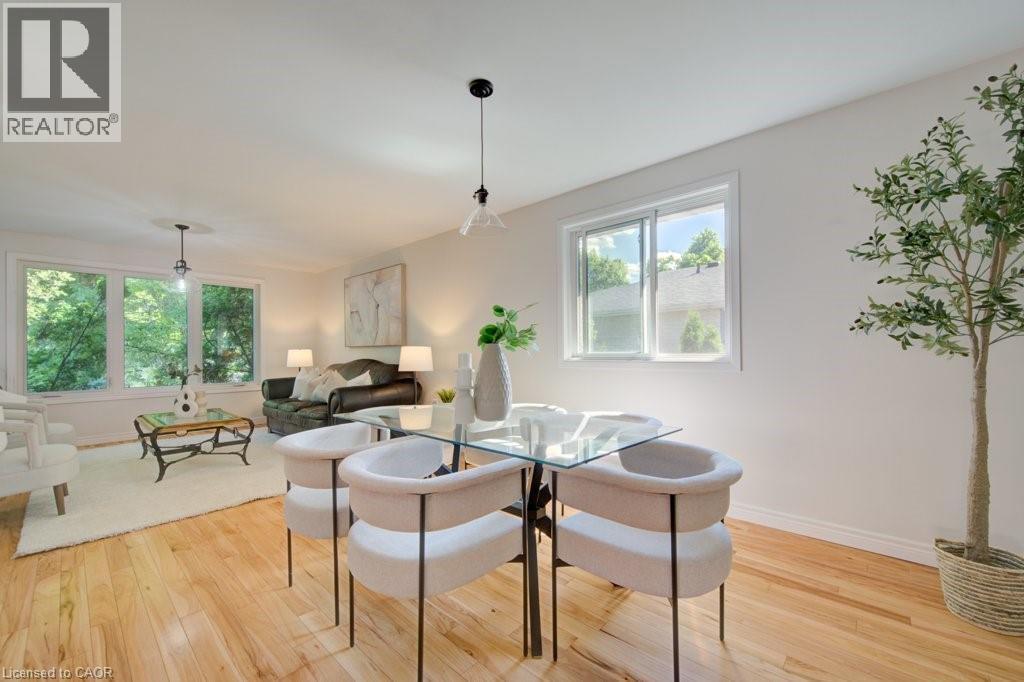 Open-concept room featuring light wood-finish flooring, white walls, and bright natural light from multiple windows - 60 Mayfield Avenue, Waterloo, ON