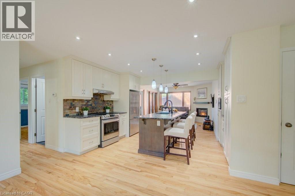 Open-concept kitchen featuring light-toned wood flooring, recessed lighting, and an expansive center island with seating - 60 Mayfield Avenue, Waterloo, ON