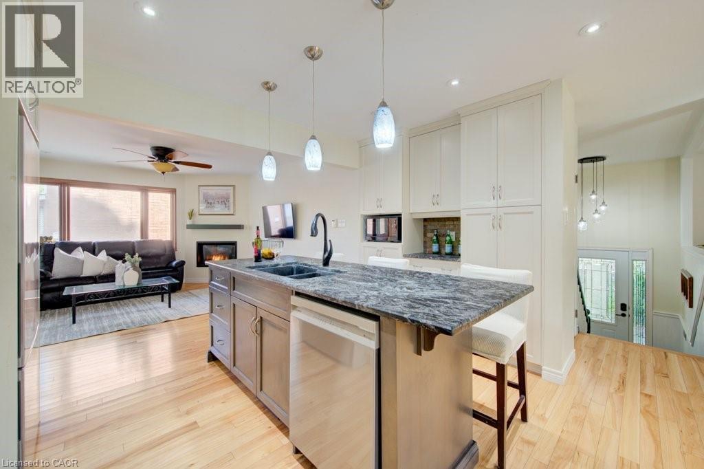 Kitchen island with stone-finish countertop, undermount sink, and integrated dishwasher - 60 Mayfield Avenue, Waterloo, ON