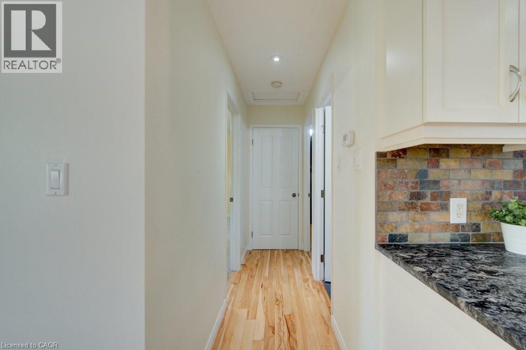 Hallway featuring wood-finish flooring, recessed lighting, and white paneled doors - 60 Mayfield Avenue, Waterloo, ON