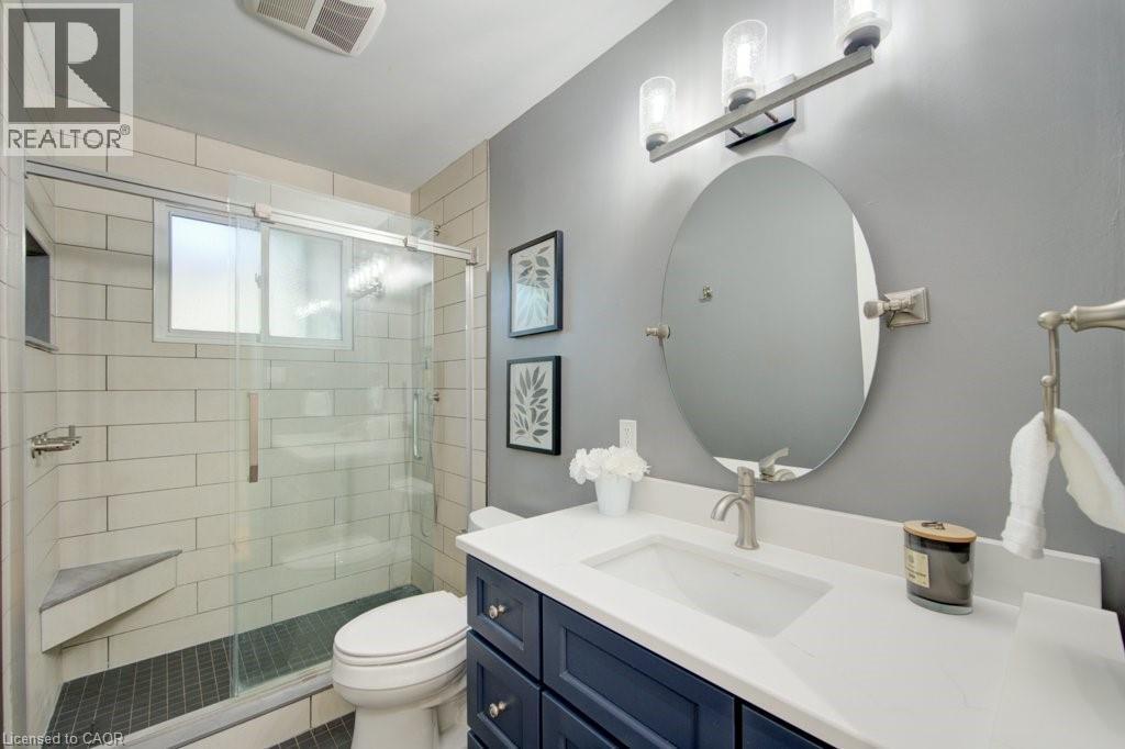 Bathroom featuring a glass-enclosed shower with a built-in bench, subway tile surround, and dark tile flooring - 60 Mayfield Avenue, Waterloo, ON