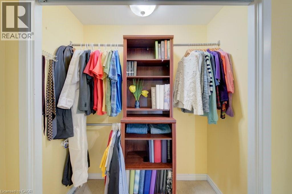 Custom closet organization system featuring a central built-in wood-finish shelving unit - 60 Mayfield Avenue, Waterloo, ON