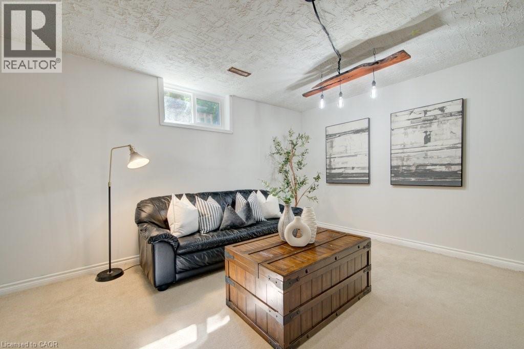 Spacious recreation room featuring light-colored carpeting, white walls, and a textured ceiling - 60 Mayfield Avenue, Waterloo, ON