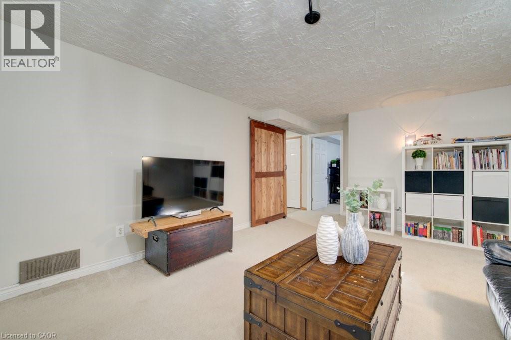 Wall-to-wall carpeting and white walls define this room, featuring a natural wood barn door - 60 Mayfield Avenue, Waterloo, ON
