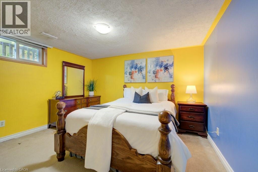 Carpeted bedroom with a window, textured ceiling, and a ceiling-mounted light fixture - 60 Mayfield Avenue, Waterloo, ON