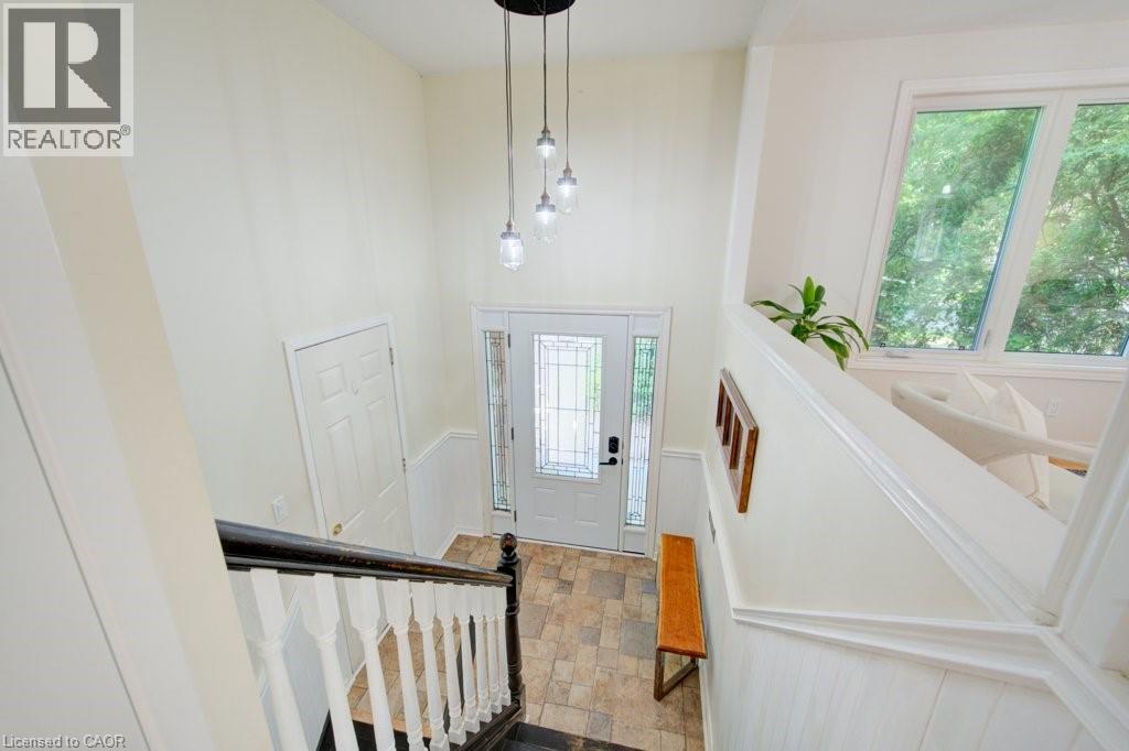 Entryway featuring a multi-light pendant fixture, leaded glass front door, tiled flooring, wainscoting, and large windows - 60 Mayfield Avenue, Waterloo, ON