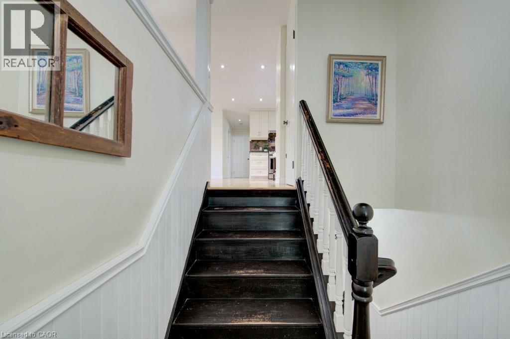 Dark-stained wood stairs with a matching handrail and white balusters - 60 Mayfield Avenue, Waterloo, ON