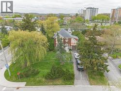 Tudor-style residence featuring a prominent gabled roof with dormer windows, brick and half-timbering facade, an attached garage, and a long paved driveway -