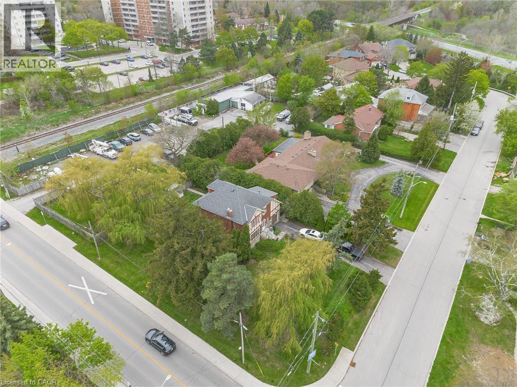 Residential property featuring a distinctive brick and shingle-style roofline, mature trees, and a paved driveway - 262-270-276 Hixon Road, Hamilton, ON