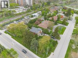 Residential property featuring a distinctive brick and shingle-style roofline, mature trees, and a paved driveway -