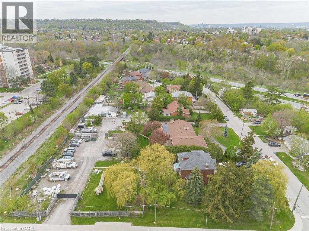Aerial perspective showcasing a residential area with varied housing styles, mature trees, and a railway line - 262-270-276 Hixon Road, Hamilton, ON
