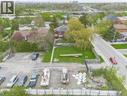Aerial perspective showcasing a residential property with a red-sided structure, a front lawn, and surrounding mature trees -
